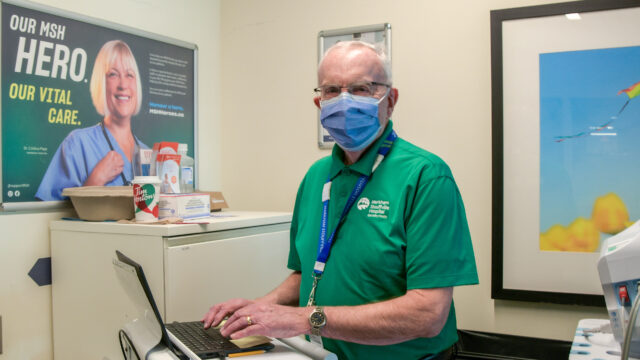 Image of Don Thompson, a volunteer who works in our Markham Stouffville Hospital’s Emergency Department, standing outside of the Emergency Department area, mask on.