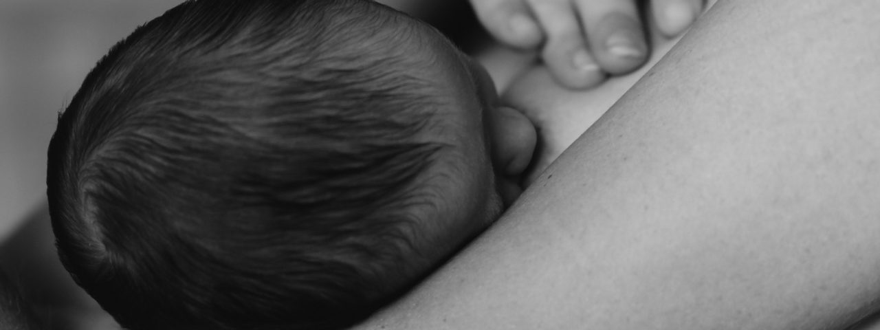 black and white image of a newborn breastfeeding