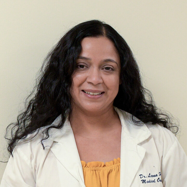Headshot of Dr. Hajra, who is wearing a yellow shirt underneath her hospital coat.
