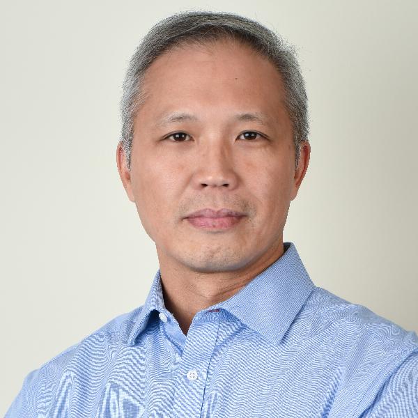 Dr. Allan Yee, seen from the chest up, wearing a blue collared shirt and short grey hair