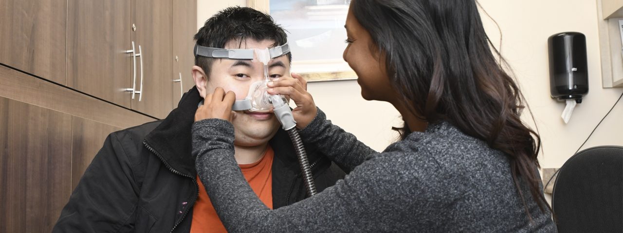 a nurse puts a CPAP machine on a patient who looks into the camera
