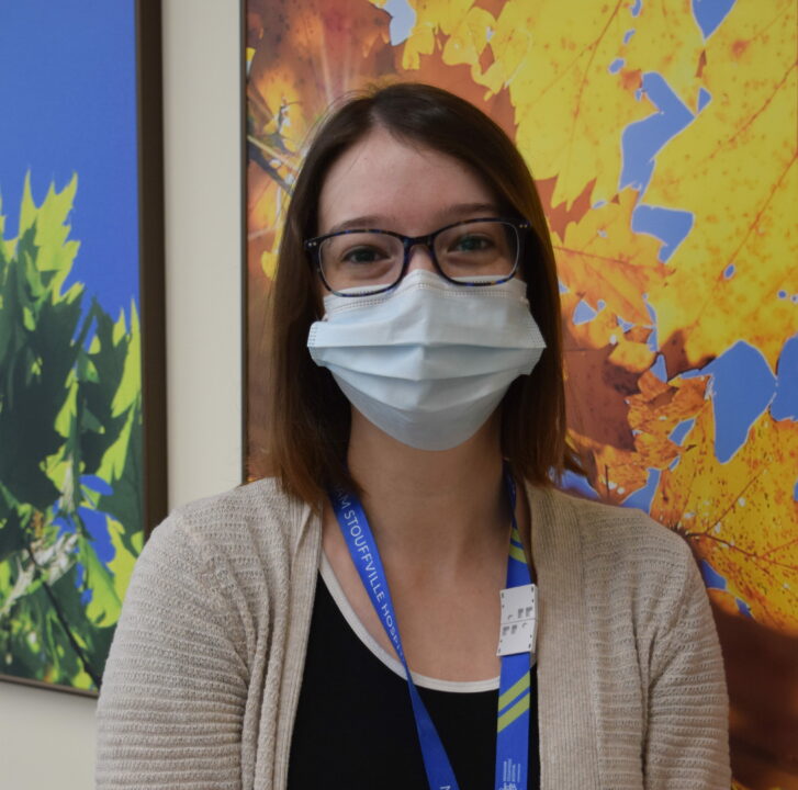 A headshot of Jessica standing up against a wall inside the hospital. She is wearing a mask.