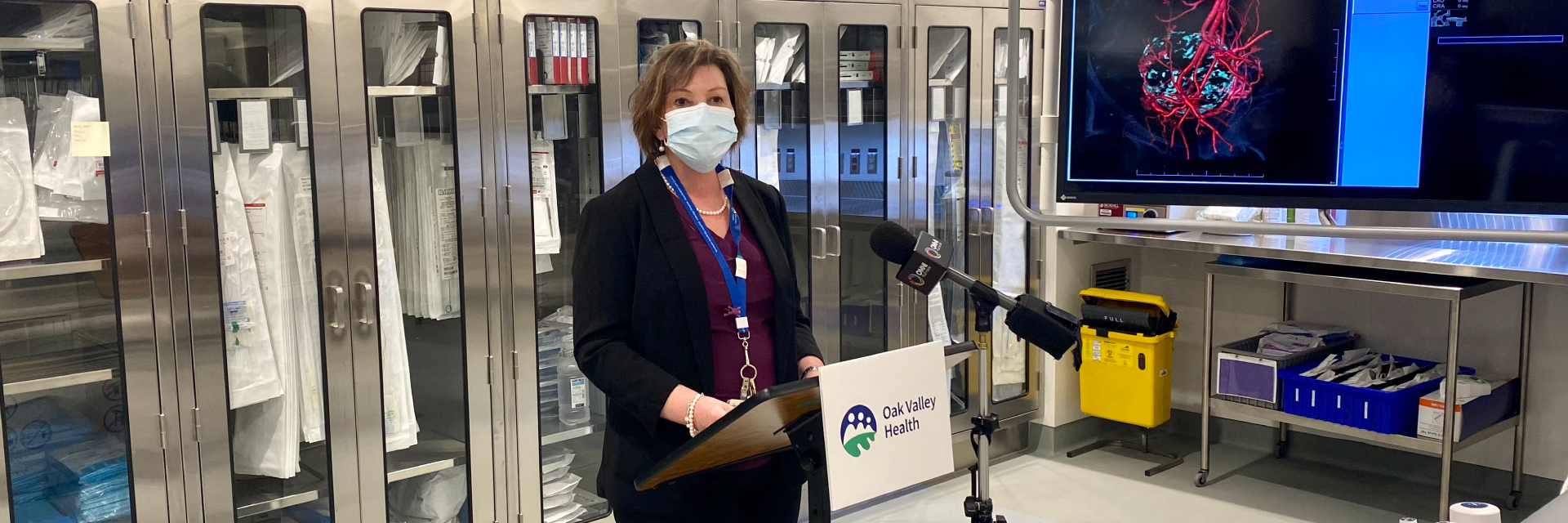 Jo-anne mar stands at a podium with a microphone and addresses the board of directors in the new radiology suite