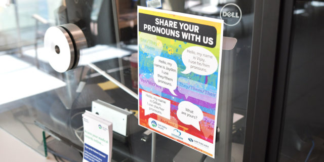 a pronoun infographic posted on a glass door