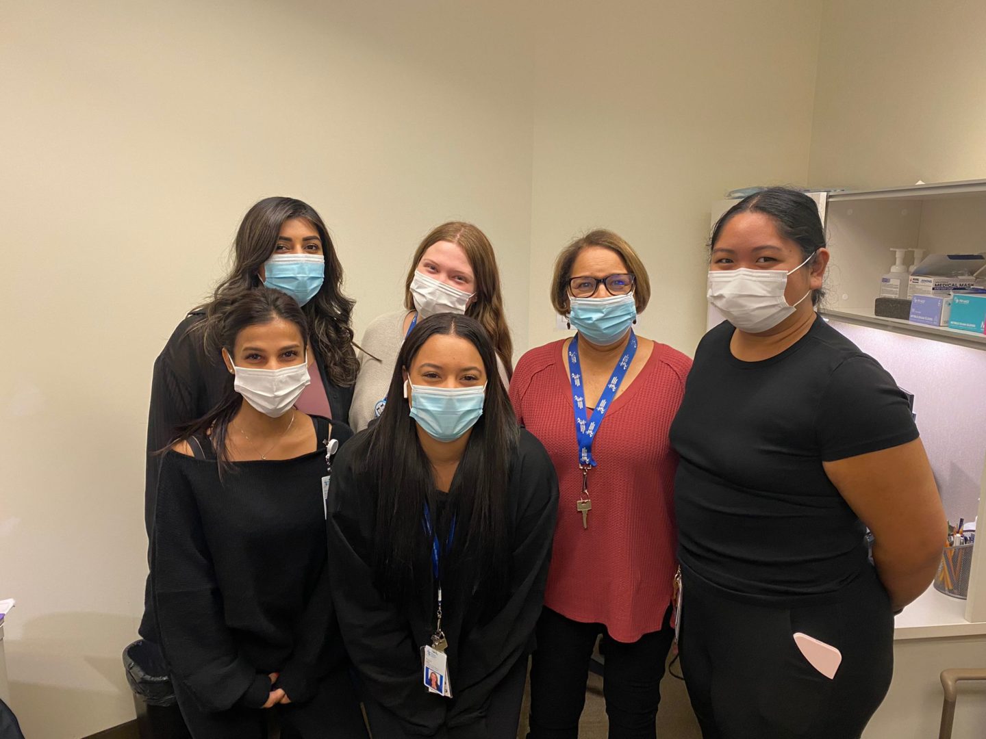 a group of women wearing medical masks stand together for a photo