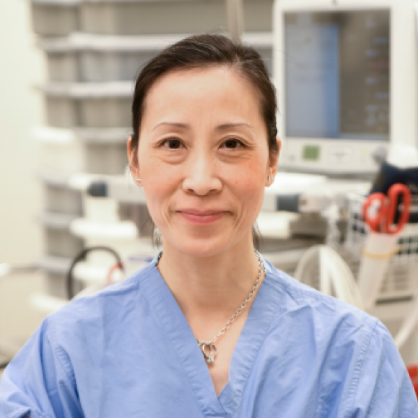 Dr. Anna Fu, seen from the shoulders up, wearing scrubs and a ponytail, smiling