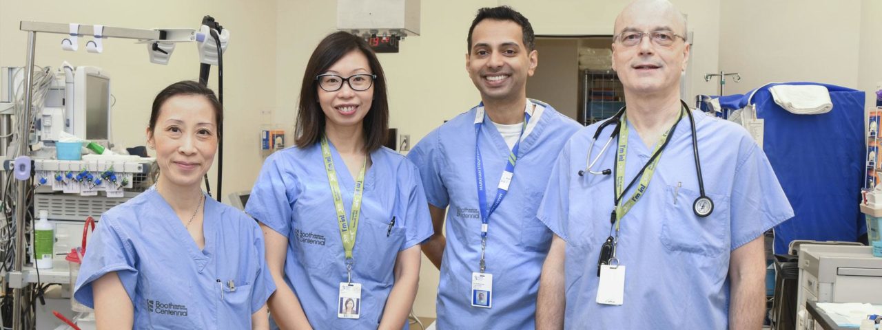 two male doctors and two female doctors, all wearing scrubs, stand together for a photo
