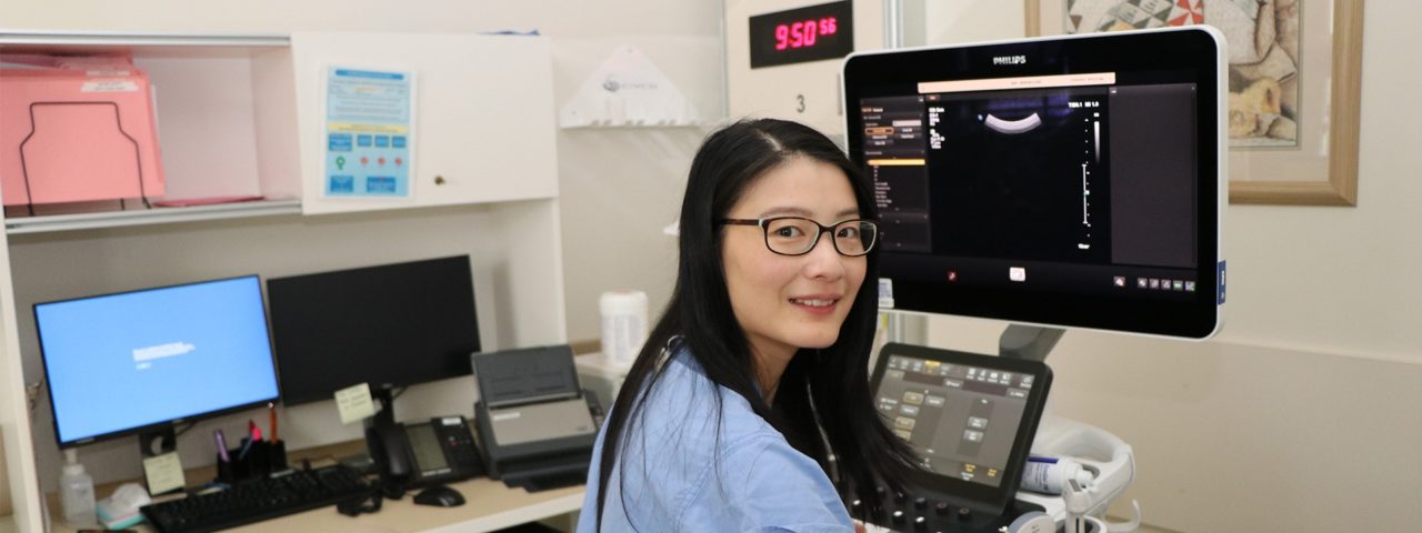 Dr. Zhang sits in front of an ultrasound machine