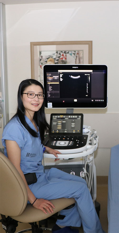 Dr. Zhang sits in front of an ultrasound machine