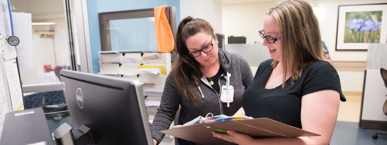 two nurses look at a clipboard together