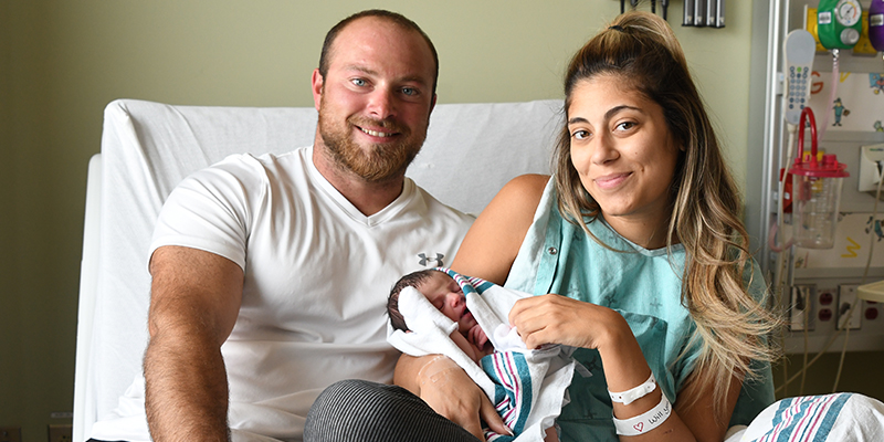 a new mother and father hold their newborn in a hospital bed