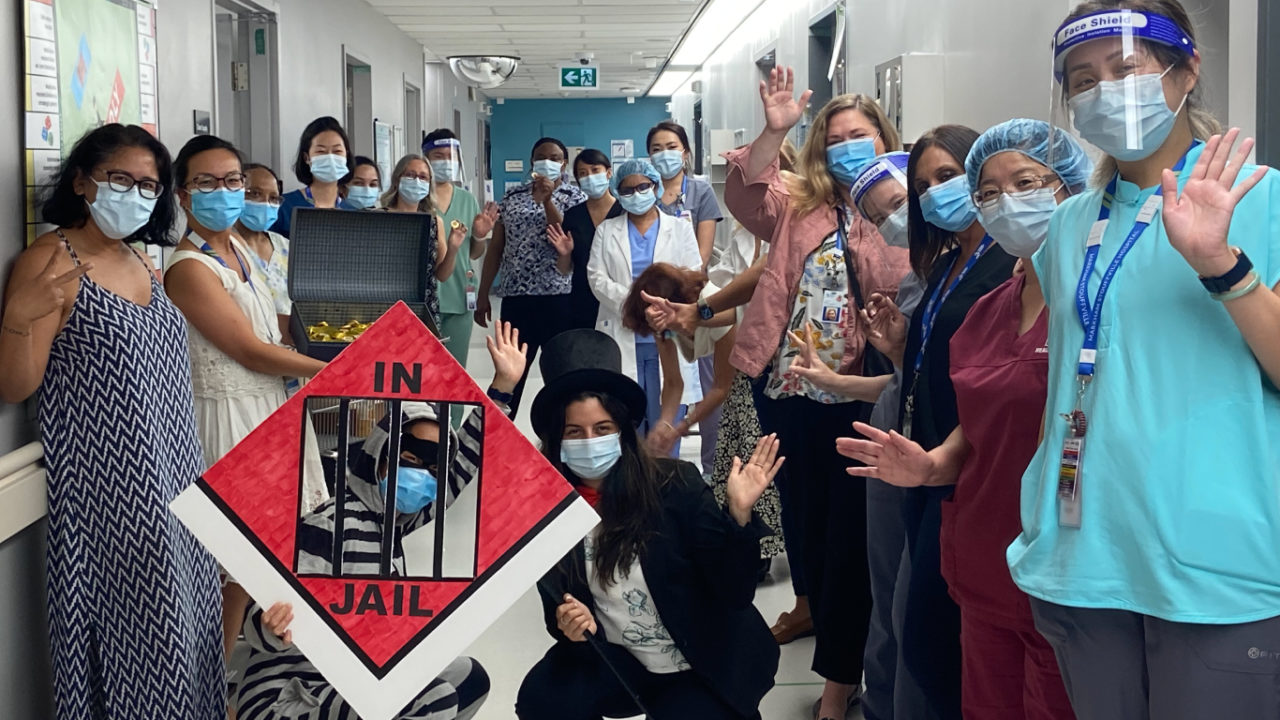 a group of doctors and nurses, all wearing medical masks, stand together with monopoly parahelia and smile