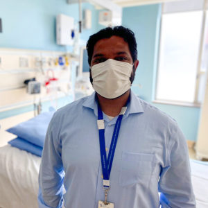 Sandeep Yakub, seen form the chest up, wearing a blue collared shirt, lanyard, short black hair, and medical mask