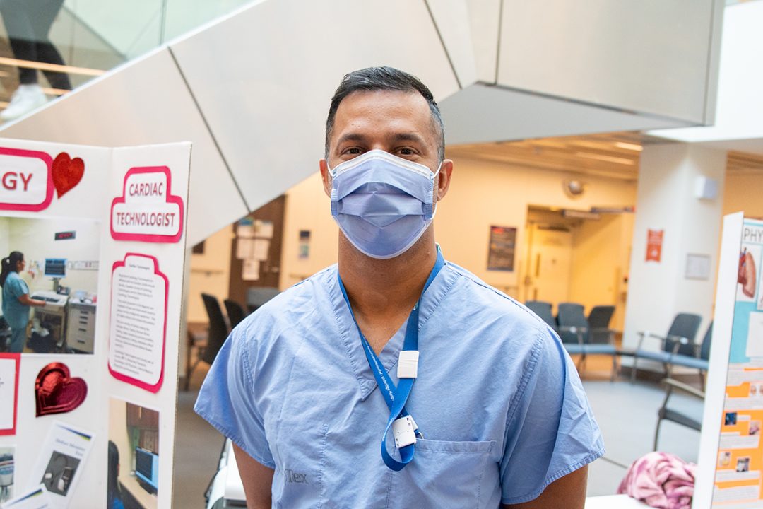 Varoon standing in the hospital lobby wearing a mask and a blue shirt.