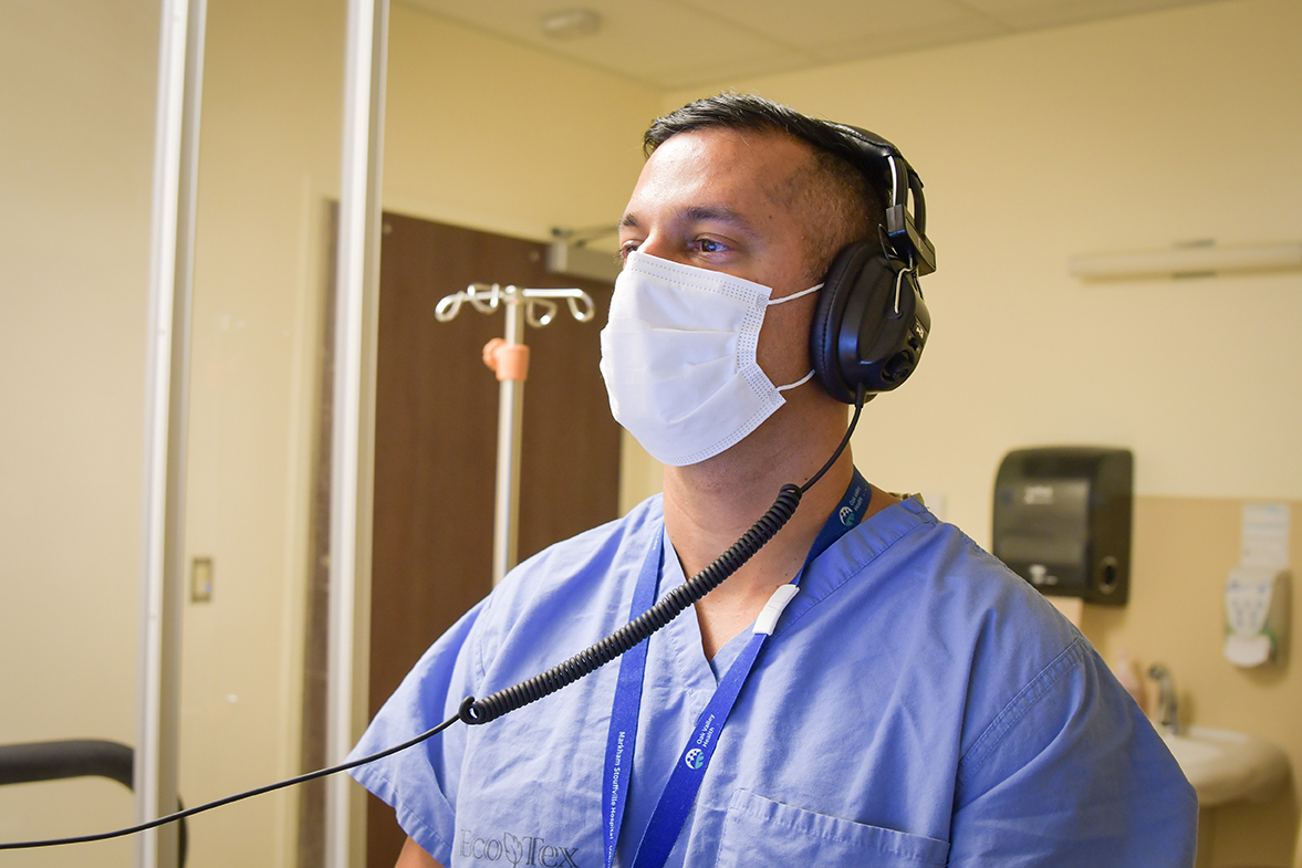 Varoon wearing headphones and a mask working in a medical office.