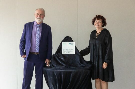 Carol and Paul stand next to a plaque recognizing their donation.