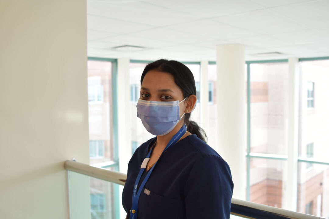 Amala posing for a photo inside the hospital lobby wearing a mask.