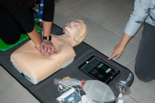 Two perform CPR on a mannequin.