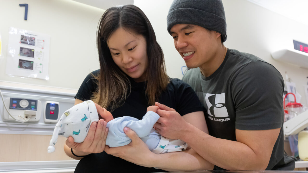 Two new parents hold their baby