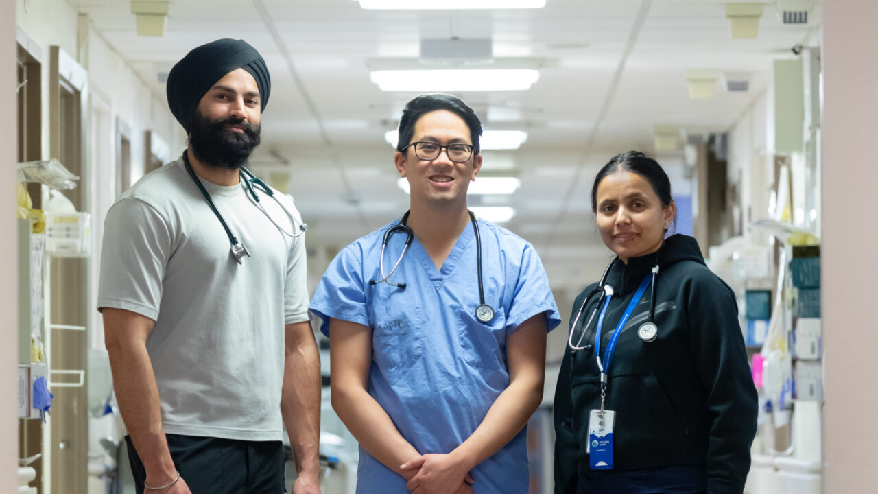 Three doctors stand shoulder-to-shoulder in the hallway at Uxbridge Hospital