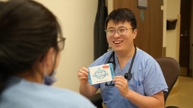 Andy Zhou sitting in a chair showing patient education information to a patient.
