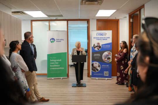 Woman standing at podium giving a speech to many surrounding her